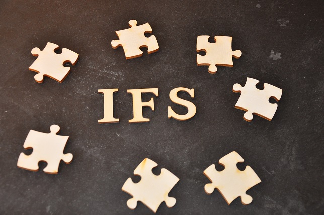 Das Wort "IFS" in Holzbuchstaben, umgeben von Puzzleteilen