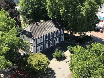 Das ifs-Haus im Sommer umgeben von grünen Laubbäumen